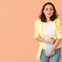 Femme souffrant de douleurs menstruelles, tenant une bouillotte sur son ventre pour soulager ses crampes. Cette image illustre l'importance des remèdes naturels et des pratiques bien-être, comme l'utilisation de la bouillotte, pour soulager les règles douloureuses.