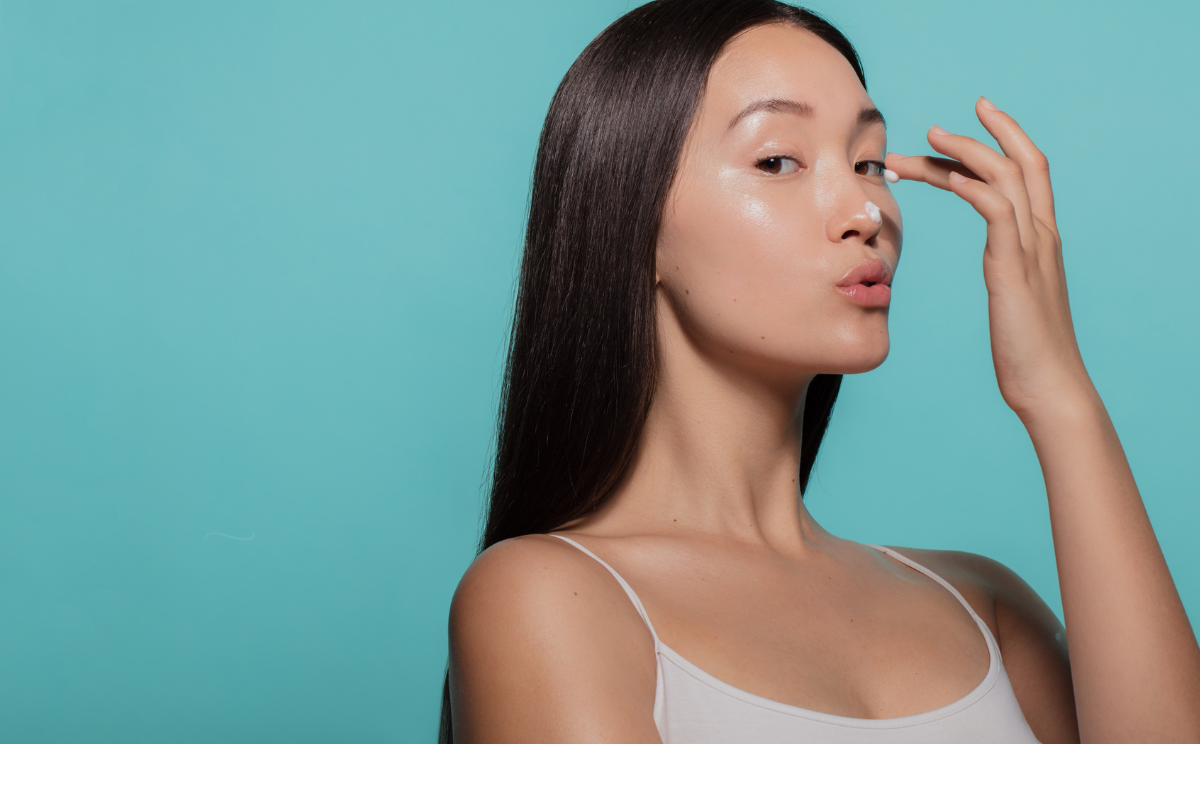 Femme appliquant de la crème sur son visage, illustrant l'utilisation de l'adapalene comme traitement anti-âge. L'adapalene, un rétinoïde de troisième génération, est reconnu pour ses propriétés anti-inflammatoires et exfoliantes, améliorant la tolérance cutanée tout en stimulant la production de collagène et le renouvellement cellulaire. Contrairement au rétinol, il offre une meilleure photostabilité et moins d'irritation, idéal pour réduire les rides et améliorer la texture de la peau.