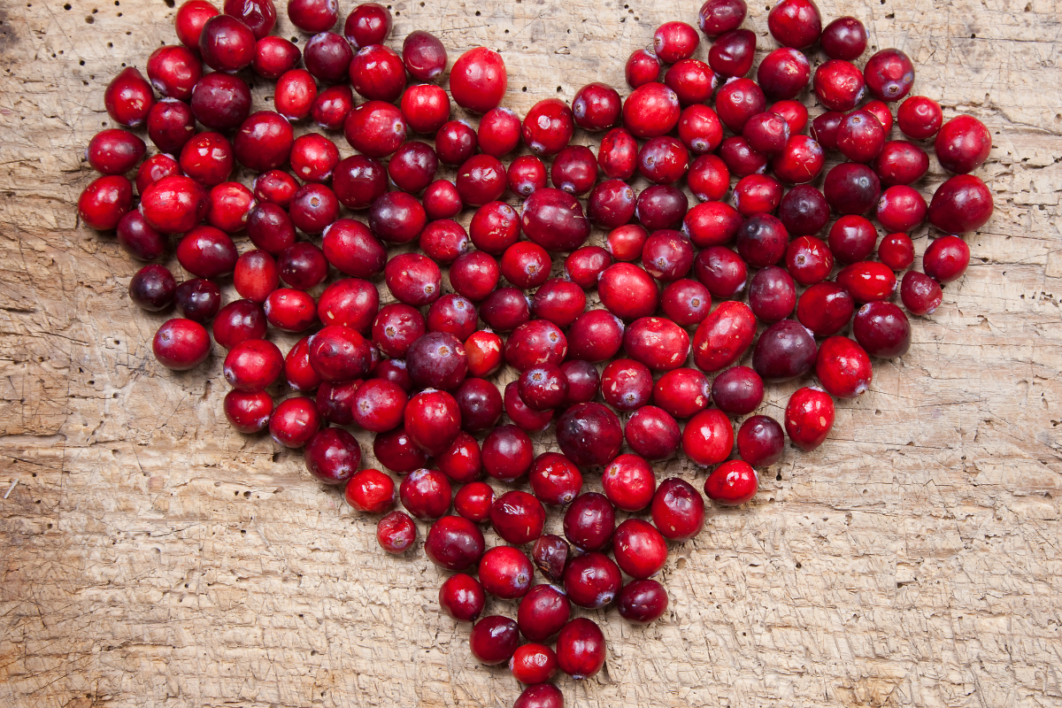 Cranberries fraîches disposées en forme de cœur sur une surface en bois, illustrant les bienfaits santé et le potentiel anticancéreux de ce superaliment.