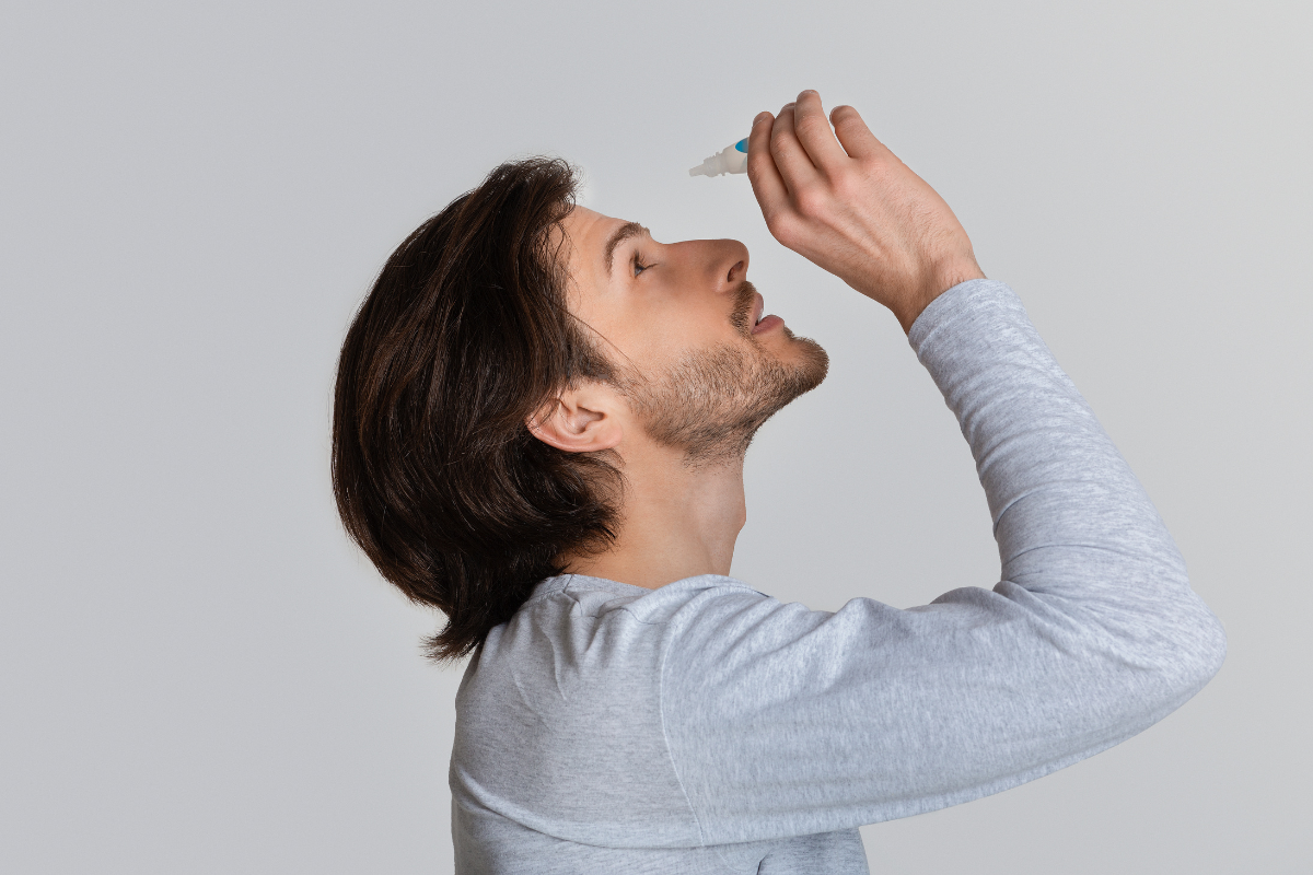 Homme appliquant des gouttes ophtalmiques pour soulager la sécheresse oculaire. Illustration de l'utilisation des larmes artificielles, traitement courant des symptômes tels que l'irritation, la rougeur et la sensation de brûlure. Solution idéale pour stabiliser le film lacrymal, améliorer l’hydratation et réduire l’inflammation oculaire liée aux yeux secs.