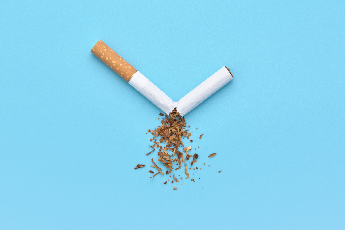 Cigarette cassée avec du tabac qui tombe sur fond bleu, symbole du sevrage tabagique naturel et de l’arrêt du tabac.